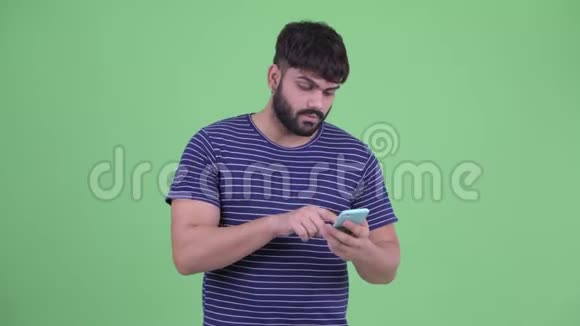 年轻的超重留胡子的印度男人在电话里讲话并表示停止手势视频的预览图