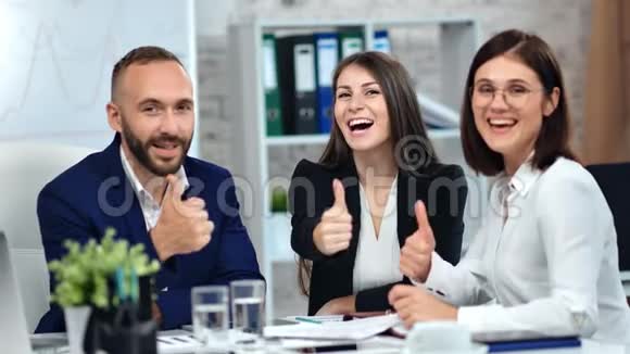 快乐的商人和女商人微笑着展示着冷静的拇指享受着公司会议的乐趣视频的预览图