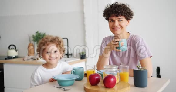 在餐桌上吃早餐的美丽家庭母亲和小儿子的肖像视频的预览图