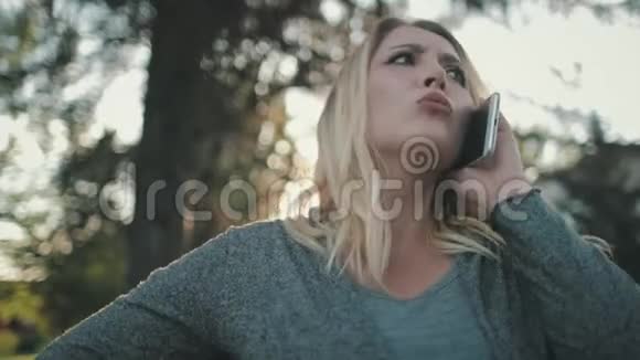 不快乐金发女人加码通话智能手机视频的预览图