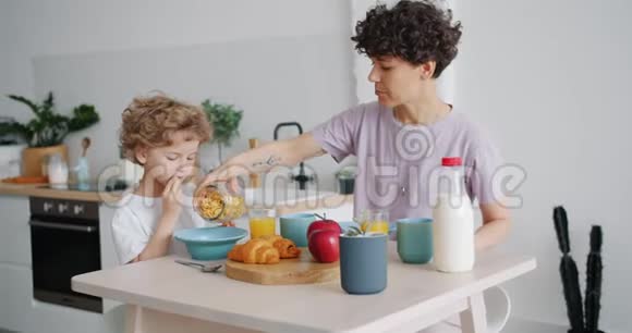在家中的厨房里有爱心的妈妈在孩子的碗里放麦片视频的预览图