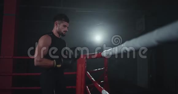 在一个黑暗拳击场中一个有魅力的强壮健美的身体男人在经过激烈的锻炼后休息视频的预览图