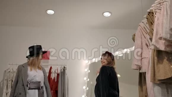 时尚的金发女性朋友在店里试穿衣服视频的预览图