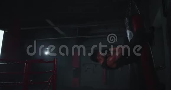 在一个黑暗的拳击课上一个跨体力概念运动的年轻人正在做腹肌练习同时用双腿握拳视频的预览图