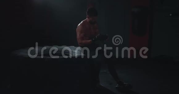 在黑暗交叉健身班运动男在经过紧张的锻炼后脱下了职业绷带视频的预览图