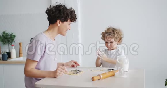 可爱的孩子拍手用面粉做饼干妈妈在厨房里视频的预览图