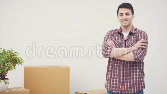 英俊的年轻人站在他的新公寓里双手交叉然后指着旁边的科普空间视频的预览图