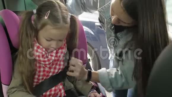 一家人去度假时美丽的有爱心的母亲把安全带系在汽车后座上视频的预览图
