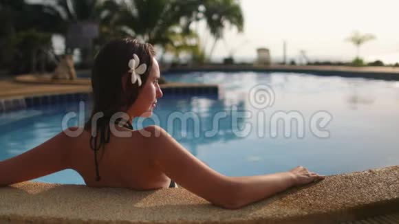 白种人女人坐在度假游泳池里视频的预览图