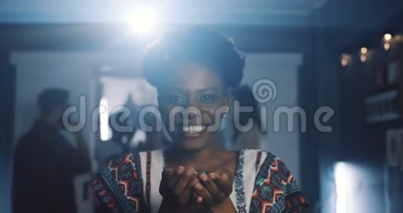 特写快乐迷人的年轻非洲女人吹着纸屑笑着在有趣的庆祝聚会慢动作视频的预览图