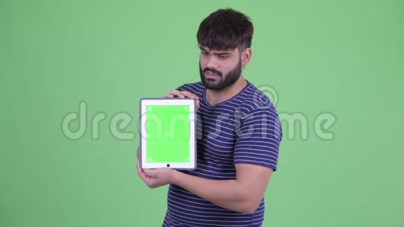 年轻体重超重留着胡须的印度男人展示数字平板电脑并得到坏消息视频的预览图