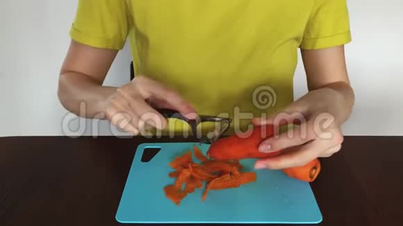 女人手在用食物剥皮机削胡萝卜女孩正在做新鲜蔬菜女孩手在削胡萝卜视频的预览图