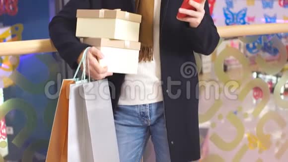 购物中心的快乐男人手里拿着圣诞礼物用智能手机视频的预览图