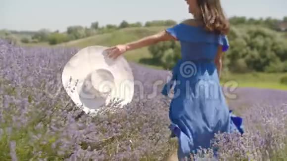 戴帽子的无忧无虑的女人穿过花丛视频的预览图
