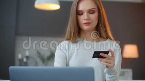 一名持有塑料银行卡和笔记本电脑的妇女从事支付和网上银行业务视频的预览图