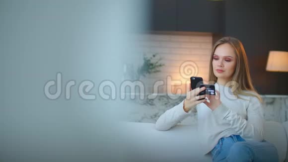 一个女人在网上用智能手机和一张坐在家里的银行卡购物视频的预览图