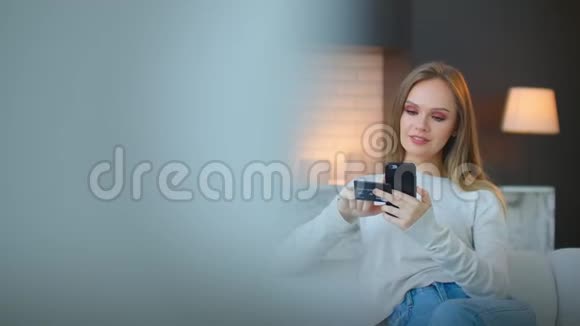 美丽的年轻女性表情开朗持有智能手机和信用卡在网上银行或购物时视频的预览图
