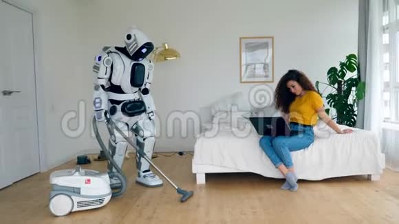 一位女士坐着笔记本电脑一个机器人正在打扫卫生视频的预览图