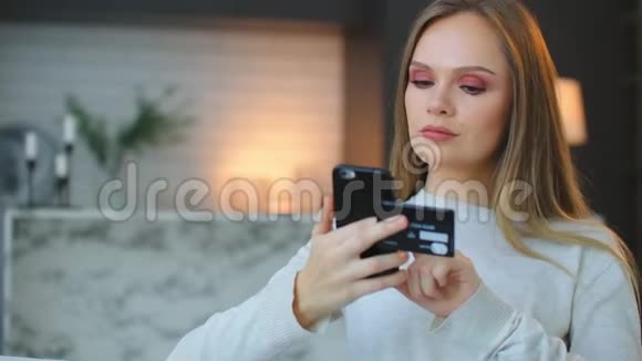 快乐女人用智能手机用银行卡在线支付的慢动作一个女人在网上用视频的预览图