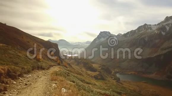 在秋天的小路上步行到树林山谷湖和雪骑在日落与耀斑阳光明媚的秋日五彩缤纷的远足视频的预览图