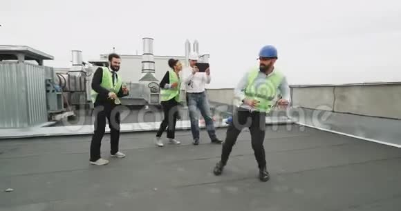 一个令人钦佩的建筑工人和他的朋友在一个建筑屋顶上享受他的时光而一个人如果一个白人视频的预览图