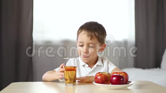 快乐的孩子坐在房间的桌子旁喝苹果汁儿童健康食品的概念视频的预览图