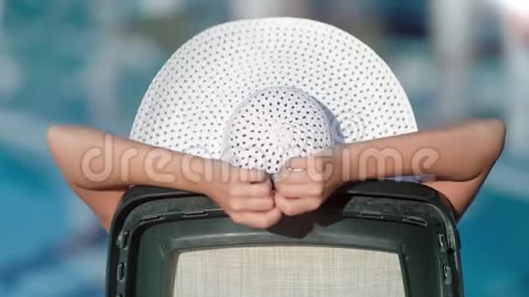 度假时晒黑的人戴着白帽子在甲板椅上放松享受日光浴的后景视频的预览图