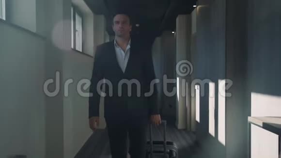 帅哥带着手提箱走在酒店大厅里住在商务酒店的男人视频的预览图