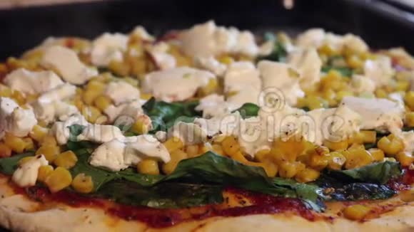 从烤箱里取出美味的素食披萨山羊奶酪菠菜叶玉米牛至胡椒视频的预览图