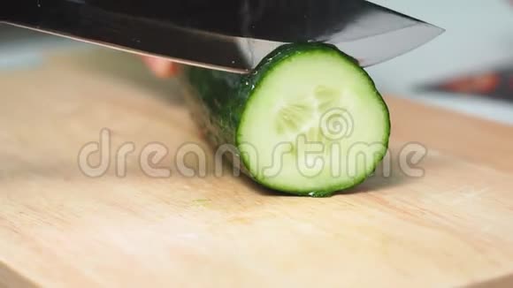 一个人用手在木切割板上用刀切黄瓜沙拉的成分特写选择性视频的预览图