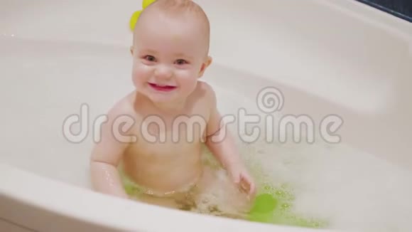 小男孩坐在浴缸里用肥皂泡沫和玩他的嘴在慢动作中弹4K镜头玩视频的预览图