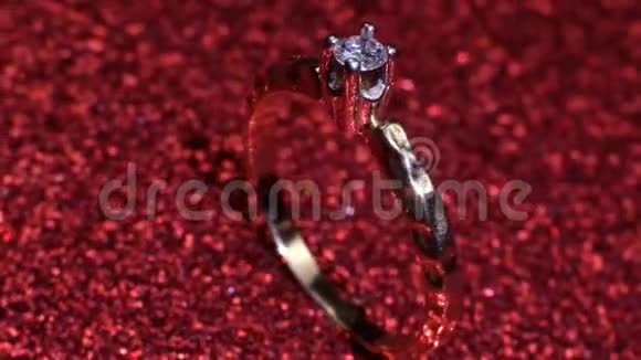 美丽闪亮的金色订婚戒指与大宝石钻石在闪光的红色背景情人节礼物视频的预览图