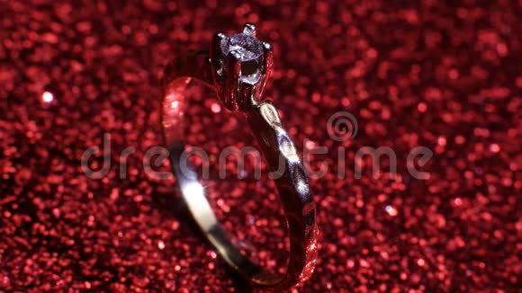 美丽闪亮的金色订婚戒指与大宝石钻石在闪光的红色背景情人节礼物视频的预览图