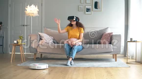 一位穿着VR眼镜的女士和地板上的机器人胡佛机器人人形半机概念视频的预览图