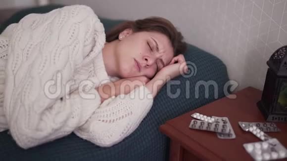 一个女人咳嗽并紧贴着她的脖子女孩喉咙痛皱着眉头药物和药片放在桌子旁边视频的预览图