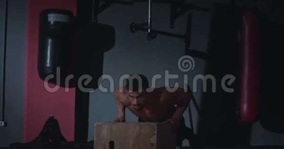 在交叉健身课上一个身材完美的年轻人在木箱上做俯卧撑他得到了甜蜜视频的预览图