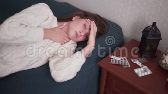 一个生病的女人看着相机紧贴着她的头头痛流感感染和温度视频的预览图