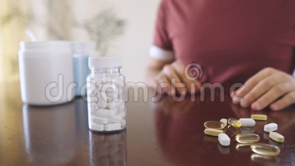 特写手端着白色的维他命和药物放在桌旁视频的预览图