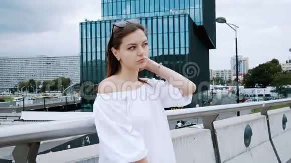 美丽的年轻商务女性站在街上的城市桥上的肖像现代蓝色玻璃办公楼视频的预览图