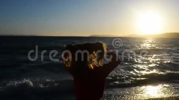 黄昏时分一位年轻女子站在海边享受生活视频的预览图