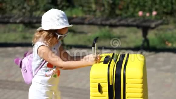 沉重的行李带黄色大手提箱的儿童游客等待旅行的小女孩视频的预览图