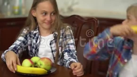 两个可爱的孩子在厨房里开玩笑地用香蕉一样的武器互相打架男孩和女孩花时间视频的预览图
