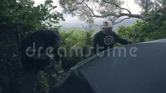 两名男子露营者在森林露营中安装帐篷以与自然保持团结视频的预览图