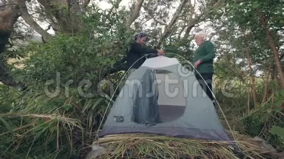 游客两个人在森林露营中组装帐篷一起度假视频的预览图