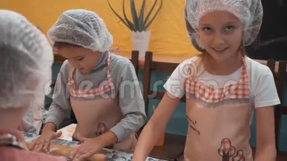 在烹饪学校的烹饪课上年轻女孩用木辊擀面团准备面团的女学生视频的预览图