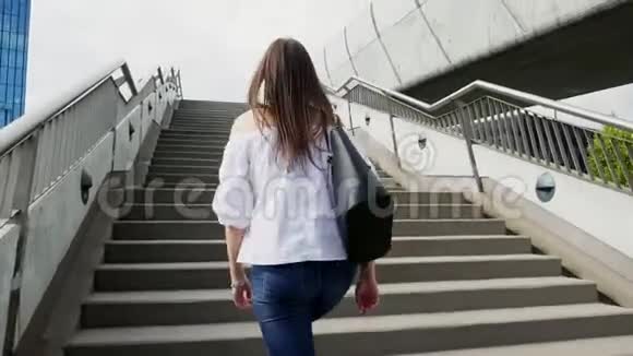 年轻女子正走在城市街道上的楼梯上视频的预览图