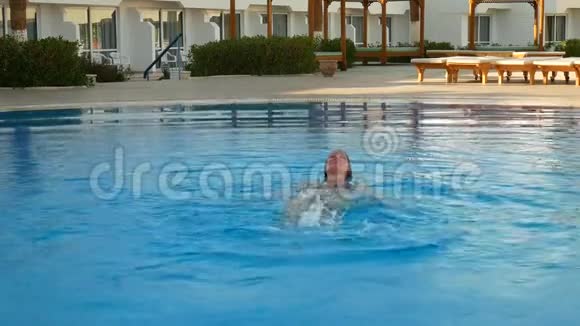 在酒店区域游泳池游泳的妇女视频的预览图