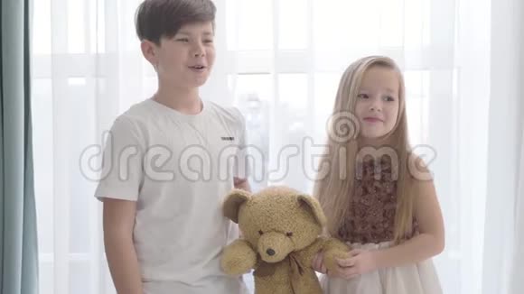 白人男孩和女孩拿着泰迪熊的肖像快乐的男人微笑着说话可爱的小女人视频的预览图