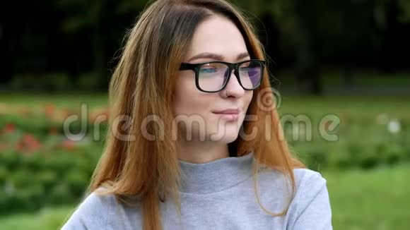 现代红发女学生戴着眼镜看镜头笑容迷人的特写肖像视频的预览图