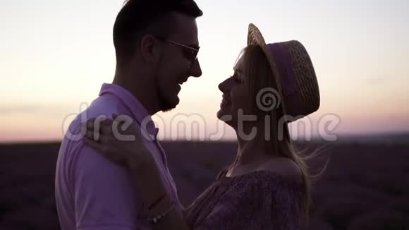 一对年轻的幸福夫妇在夕阳的背景下亲吻的特写剪影视频的预览图